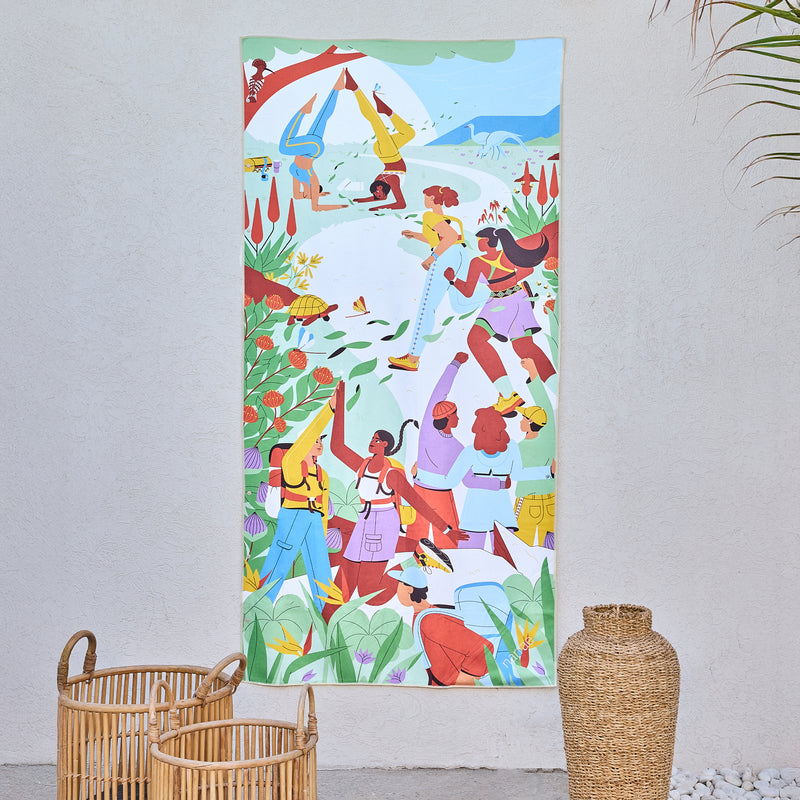 Friendship art beach towel by Studio Muti, friends hiking and celebrating outdoors, hanging on a wall