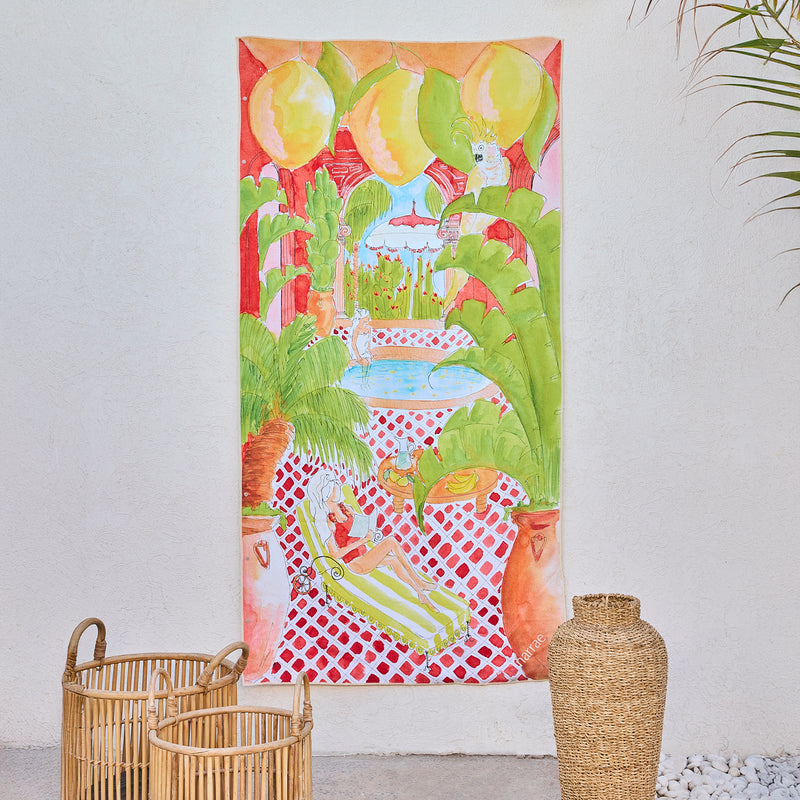 Slow Life art beach towel by Tanya Hayek, a calm spa scene with lemons and palms, hanging on a wall