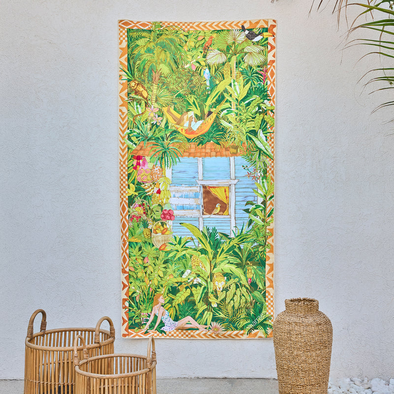 Saudade art beach towel by Gabriel Azevedo, a leafy jungle scene with a window, hanging on a white wall