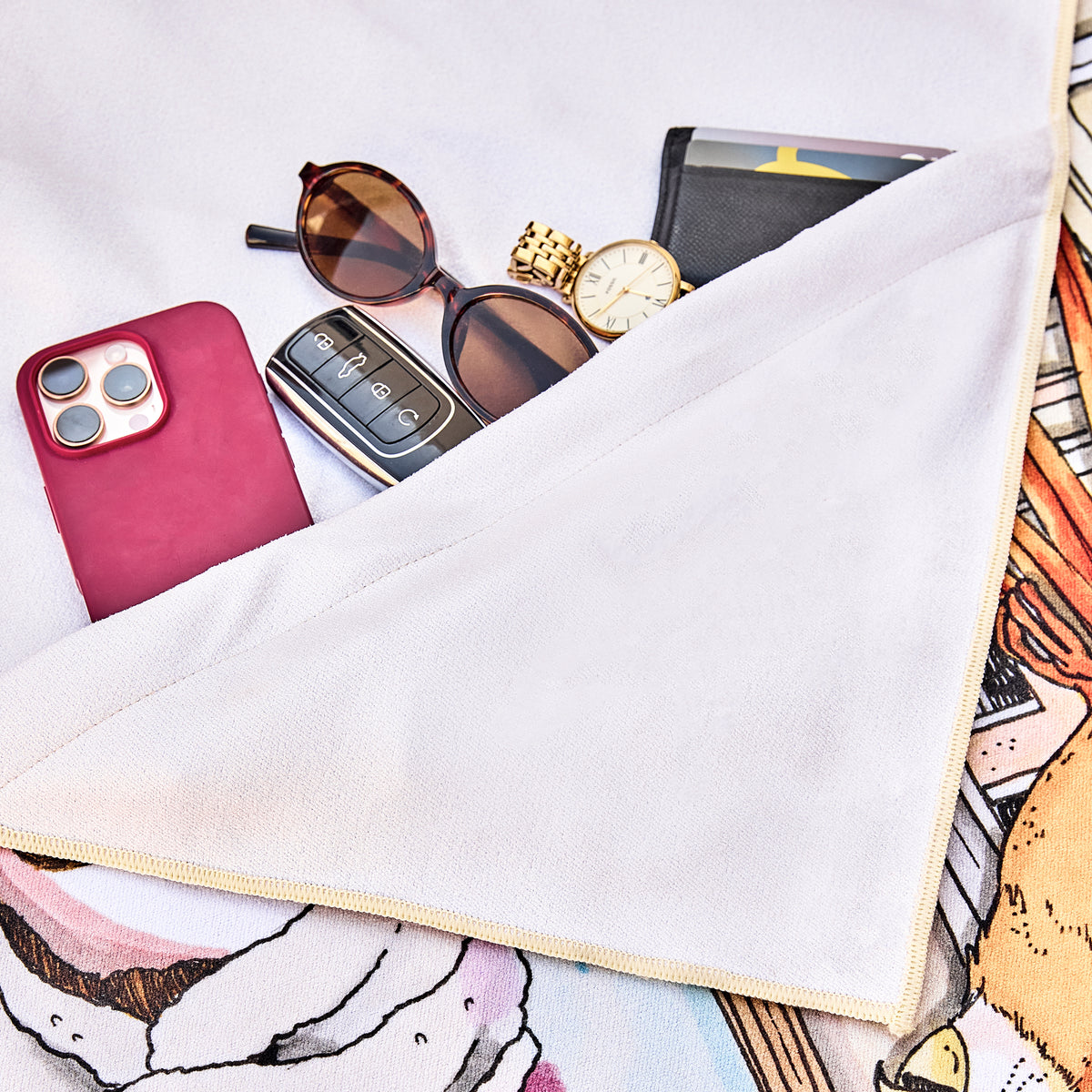 Hidden zip pocket under the Me Time beach towel holding a phone, sunglasses, keys and a watch