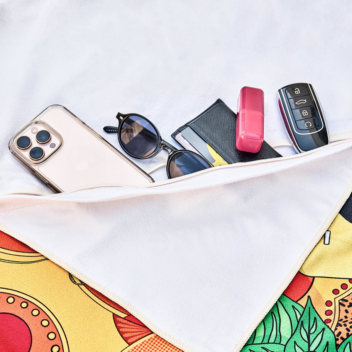 Hidden zip pocket under the Sweet Reminiscence beach towel holding a phone, sunglasses and car keys