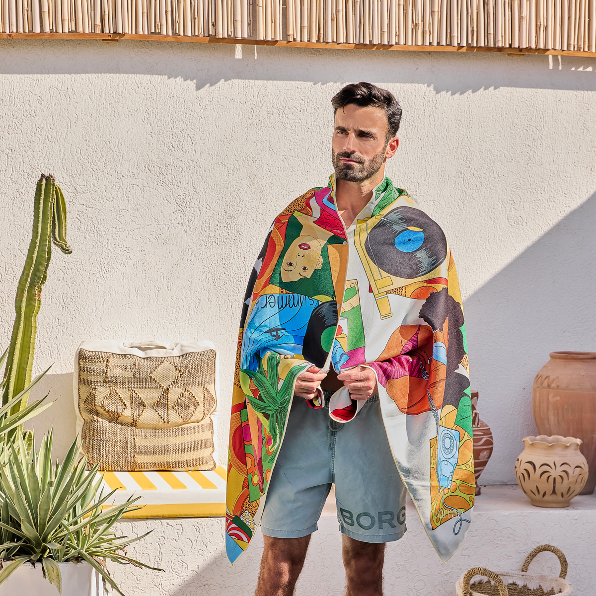 Man wearing the Sweet Reminiscence beach towel over his shoulders by a pool