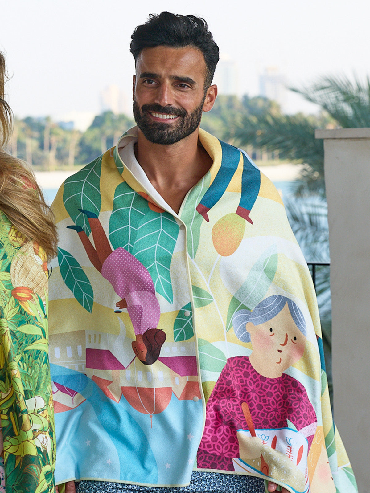 Smiling man wearing the A Journey Home beach towel as a poncho
